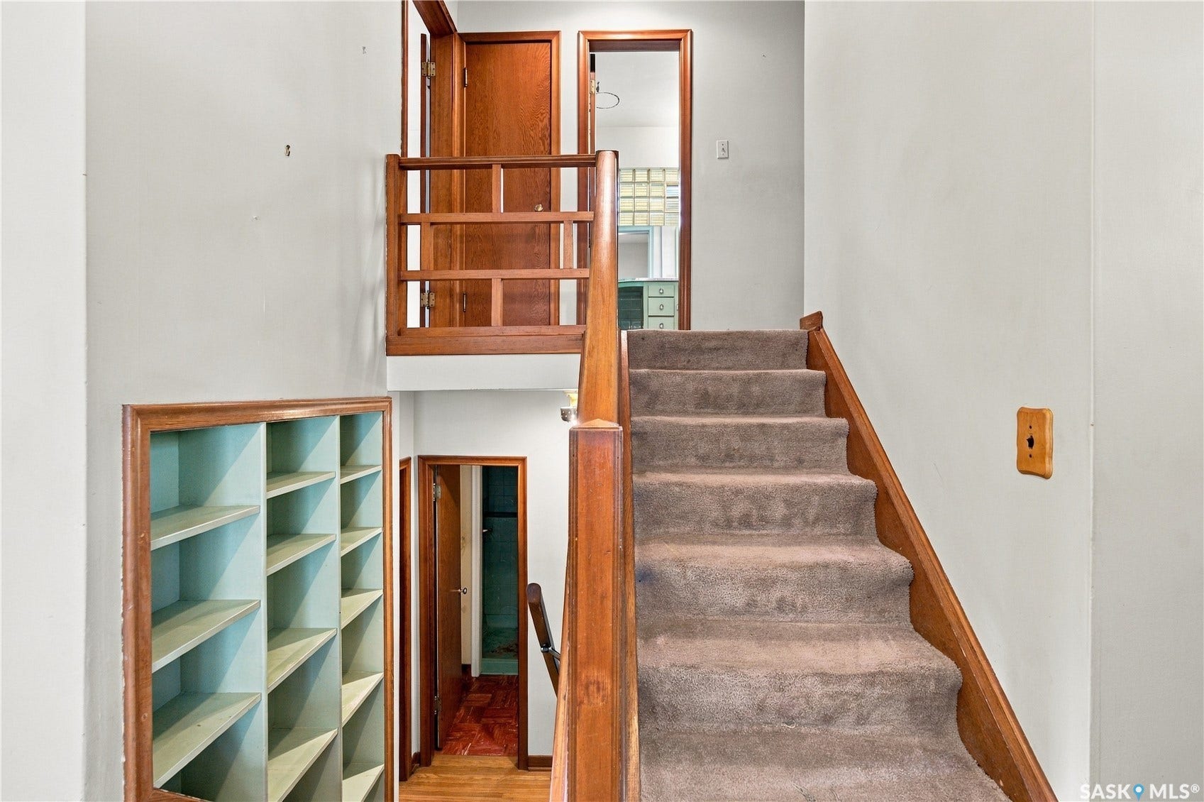 2727 Assiniboine Avenue, Regina SK S4S 1C7 Carpeted staircase with wood railing, built-in shelving, and wood-paneled doors