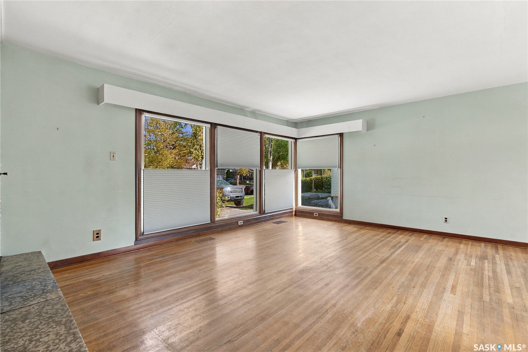 2727 Assiniboine Avenue, Regina SK S4S 1C7 Hardwood flooring, expansive windows, window treatments, and a fireplace hearth with a stone surface