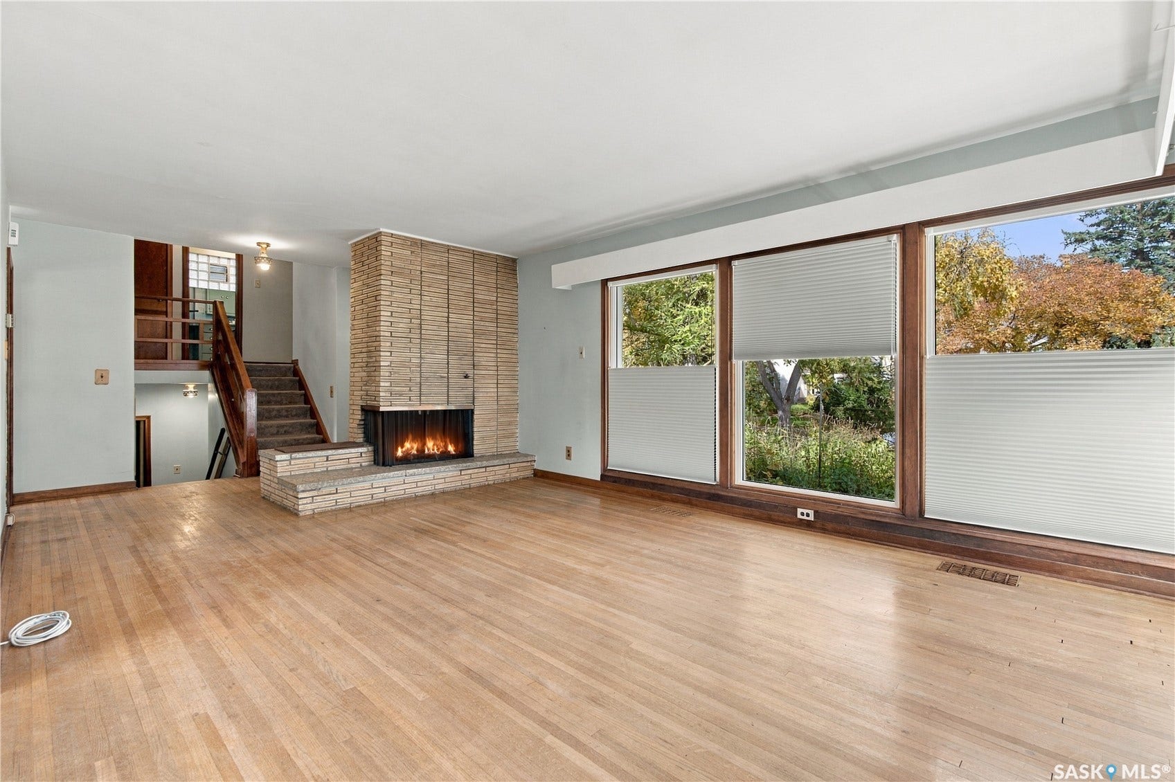 2727 Assiniboine Avenue, Regina SK S4S 1C7 Hardwood flooring throughout, stone-clad fireplace with hearth, and large windows with cellular shades