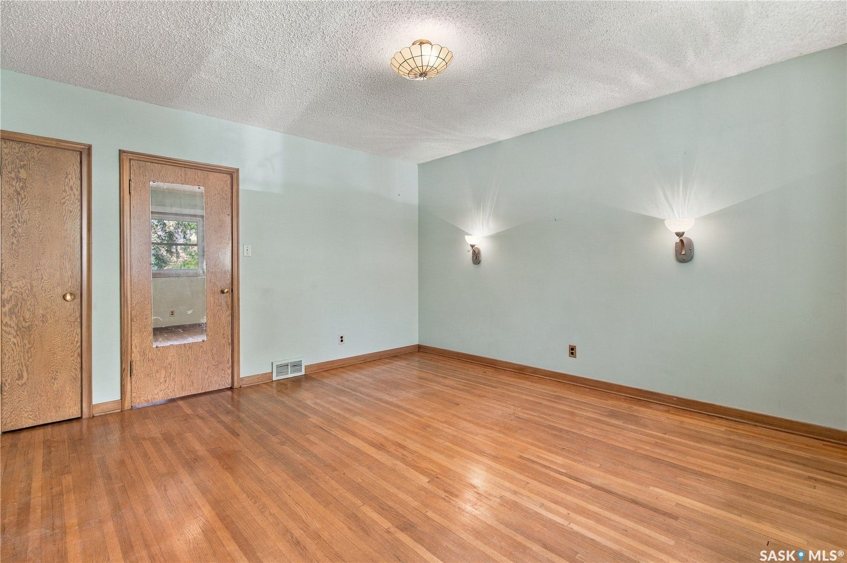 2727 Assiniboine Avenue, Regina SK S4S 1C7 Hardwood flooring complemented by light-toned wall paint and an overhead semi-flush mount light fixture