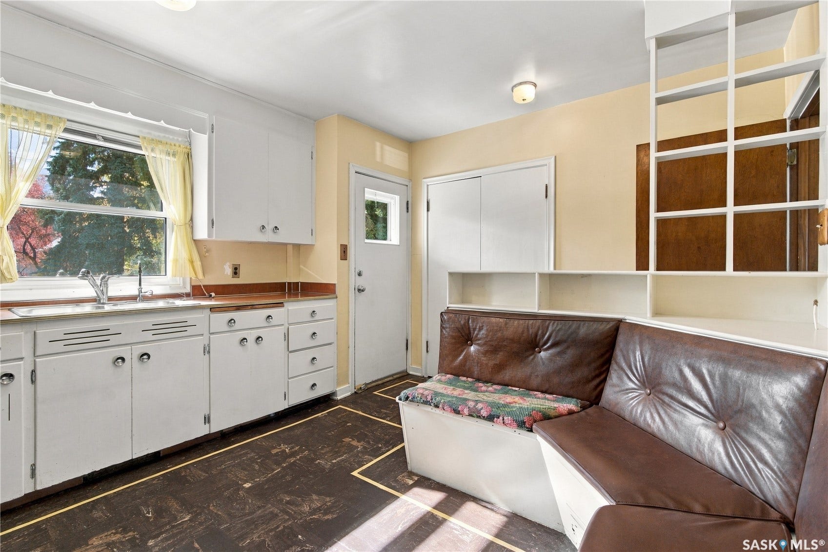 2727 Assiniboine Avenue, Regina SK S4S 1C7 White cabinetry with chrome hardware, an integrated kitchen sink, and a built-in banquette with storage