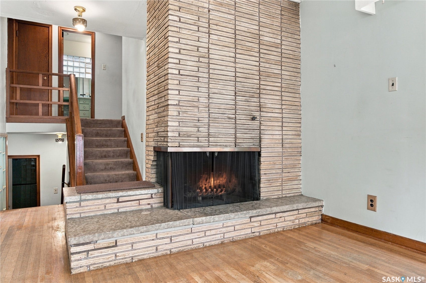 2727 Assiniboine Avenue, Regina SK S4S 1C7 Stacked stone fireplace with a stone hearth, wood-finish flooring, and a multi-level layout
