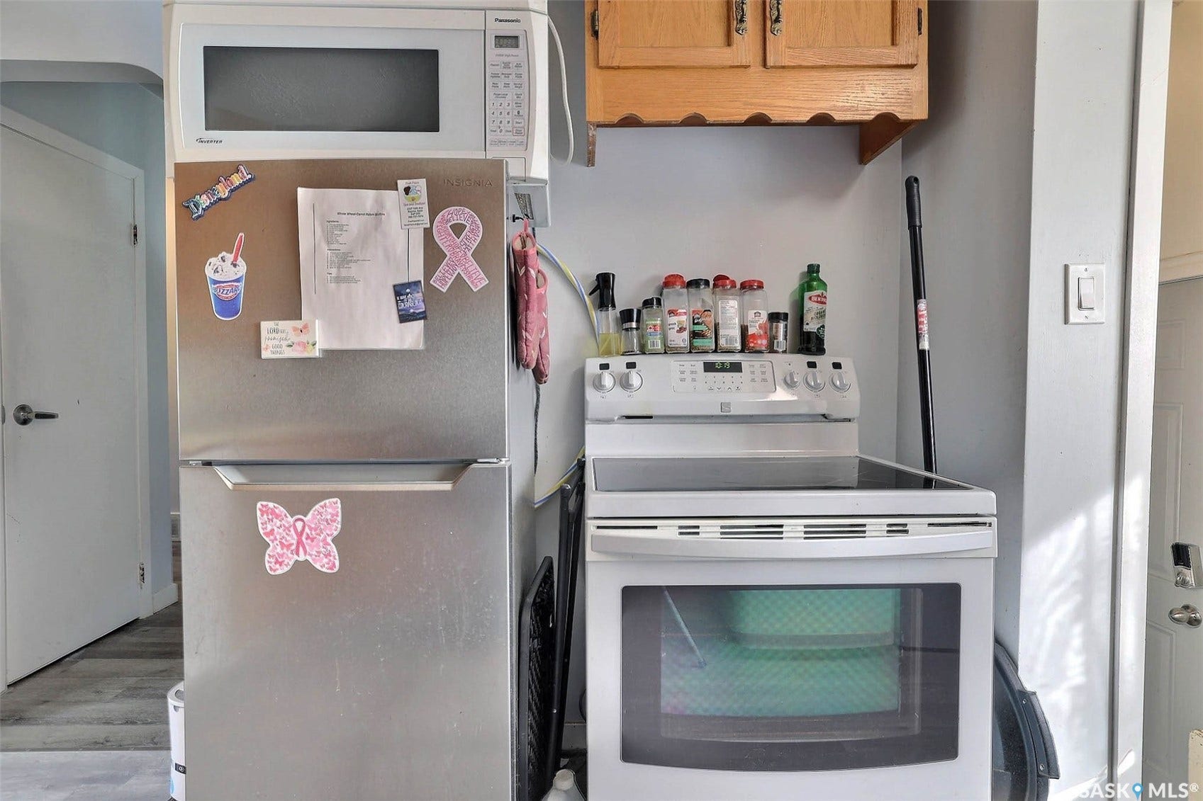 1021 Campbell Street, Regina SK S4T 5P5 Stainless steel refrigerator with freezer, white microwave, white electric range with glass cooktop, and wood-finish cabinetry