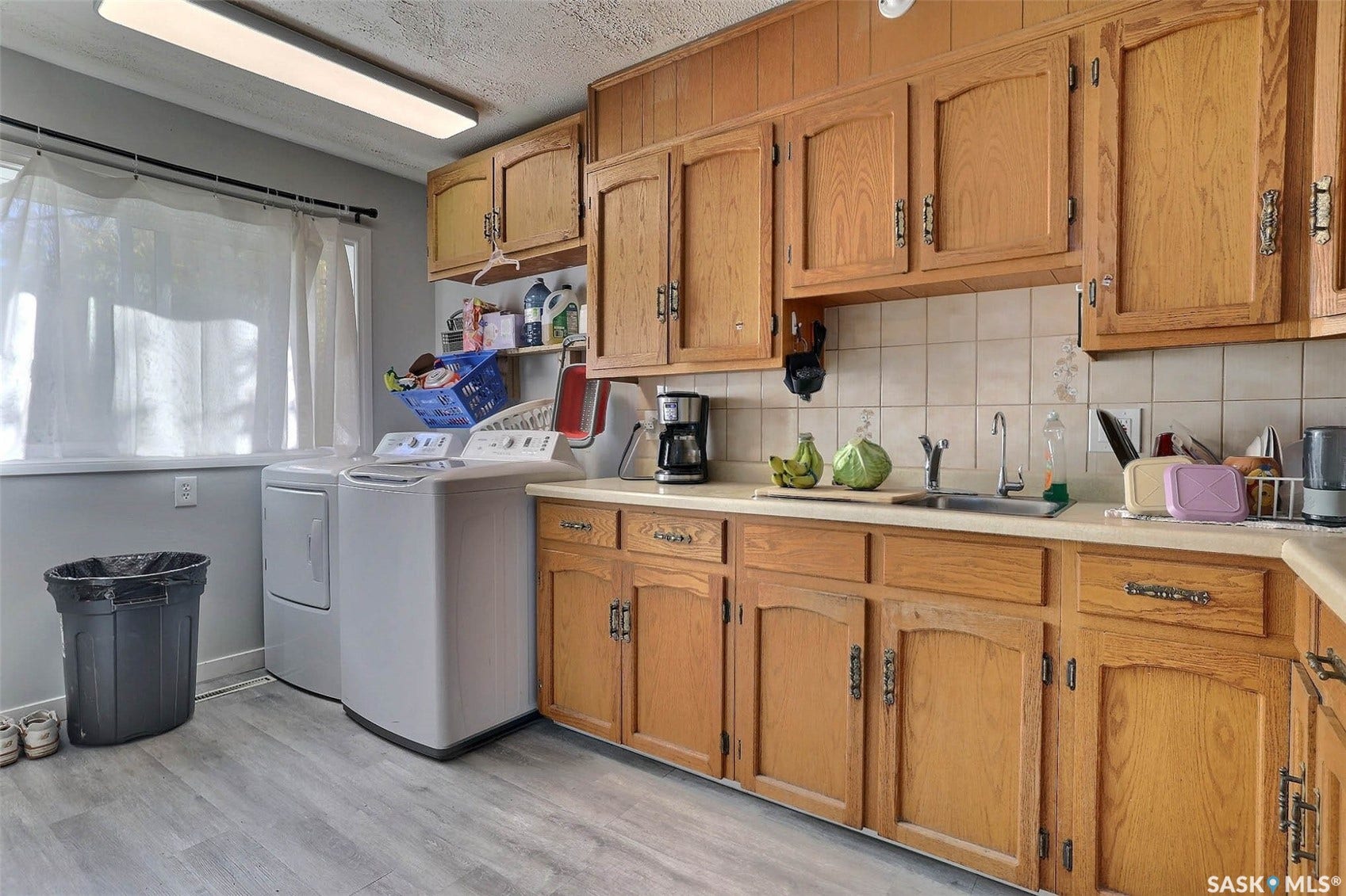 1021 Campbell Street, Regina SK S4T 5P5 Wood-finish cabinetry, tile backsplash, stainless steel sink, and wood-finish flooring