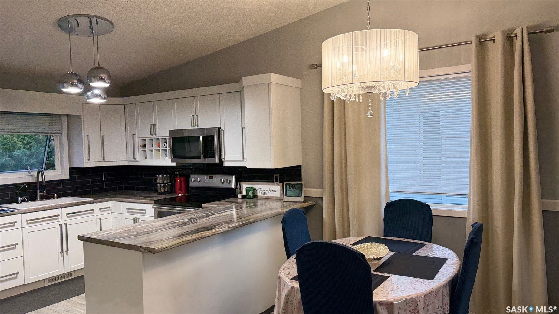 White cabinetry with chrome hardware, dark subway tile backsplash, stainless steel appliances, and a polished stone-finish countertop