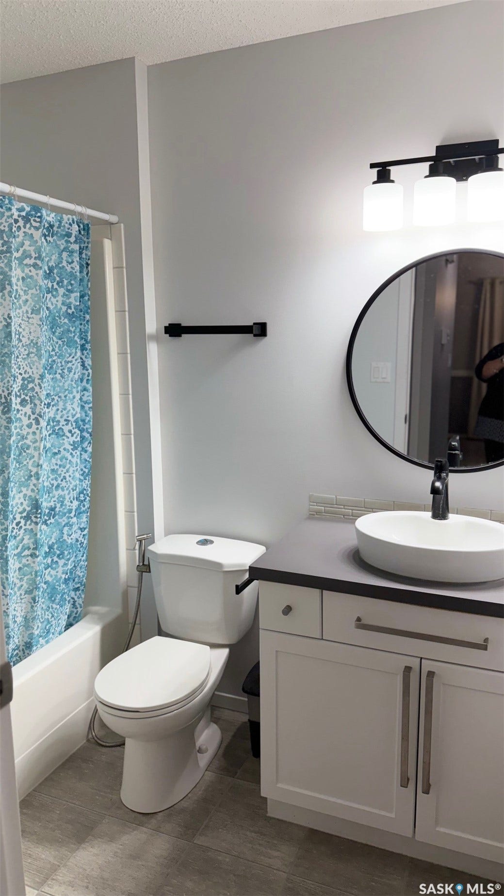 White vanity with shaker-style doors, black countertop, vessel sink, and matte black faucet