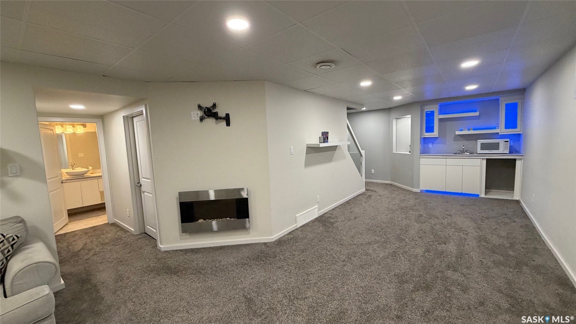 Open-concept room featuring a built-in wet bar with under-cabinet lighting, a wall-mounted electric fireplace, and recessed ceiling lighting