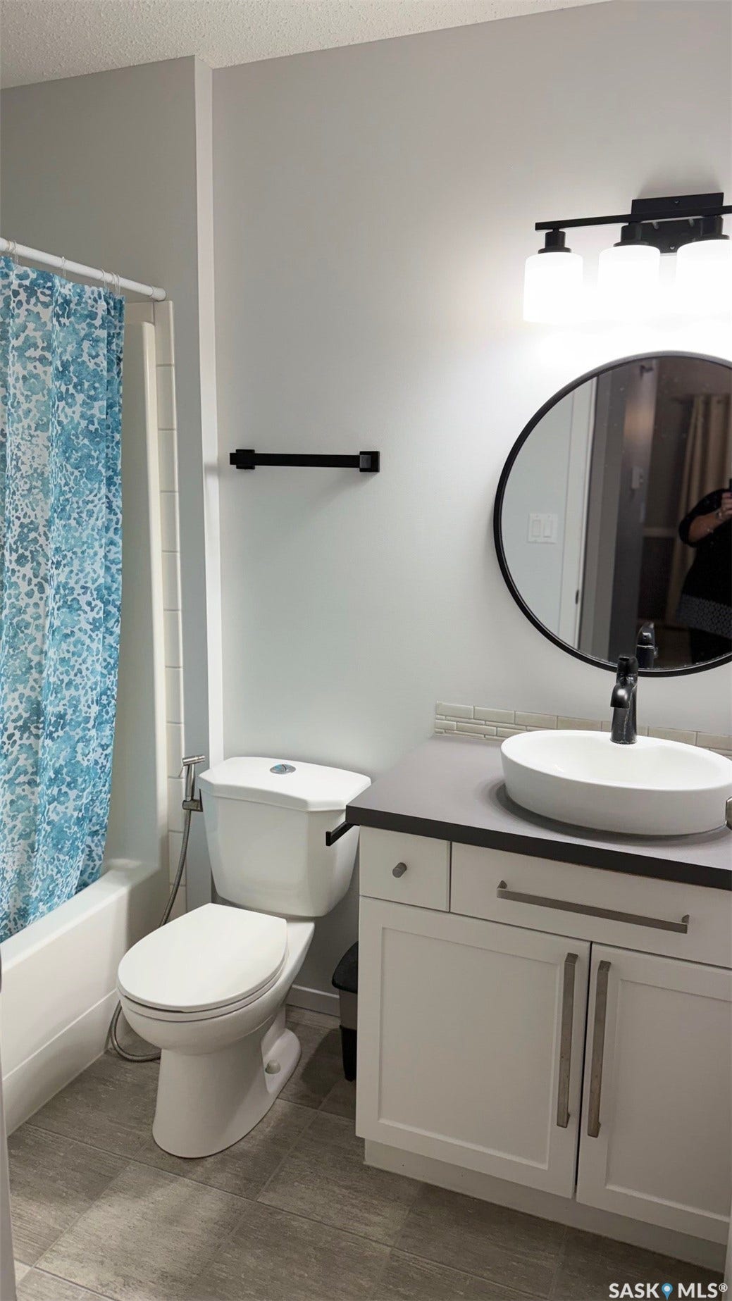 White vanity with shaker-style cabinetry, a vessel sink, and a dark countertop