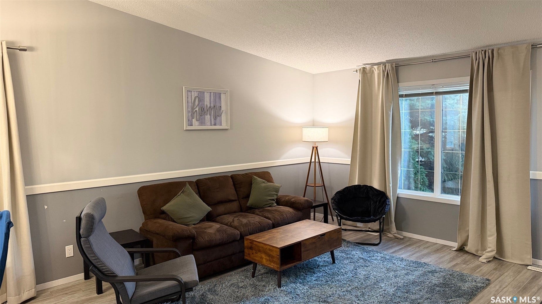 Wood-finish flooring, white trim, and a large window with natural light
