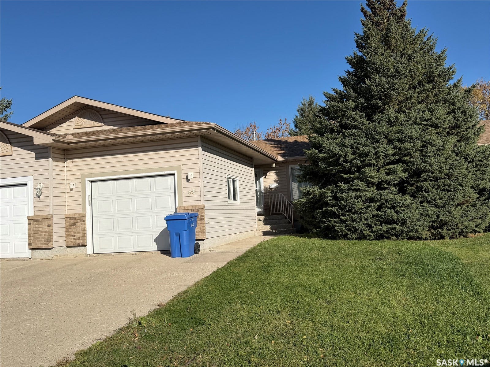 Siding exterior with brick accents, attached garage, concrete driveway, and mature landscaping