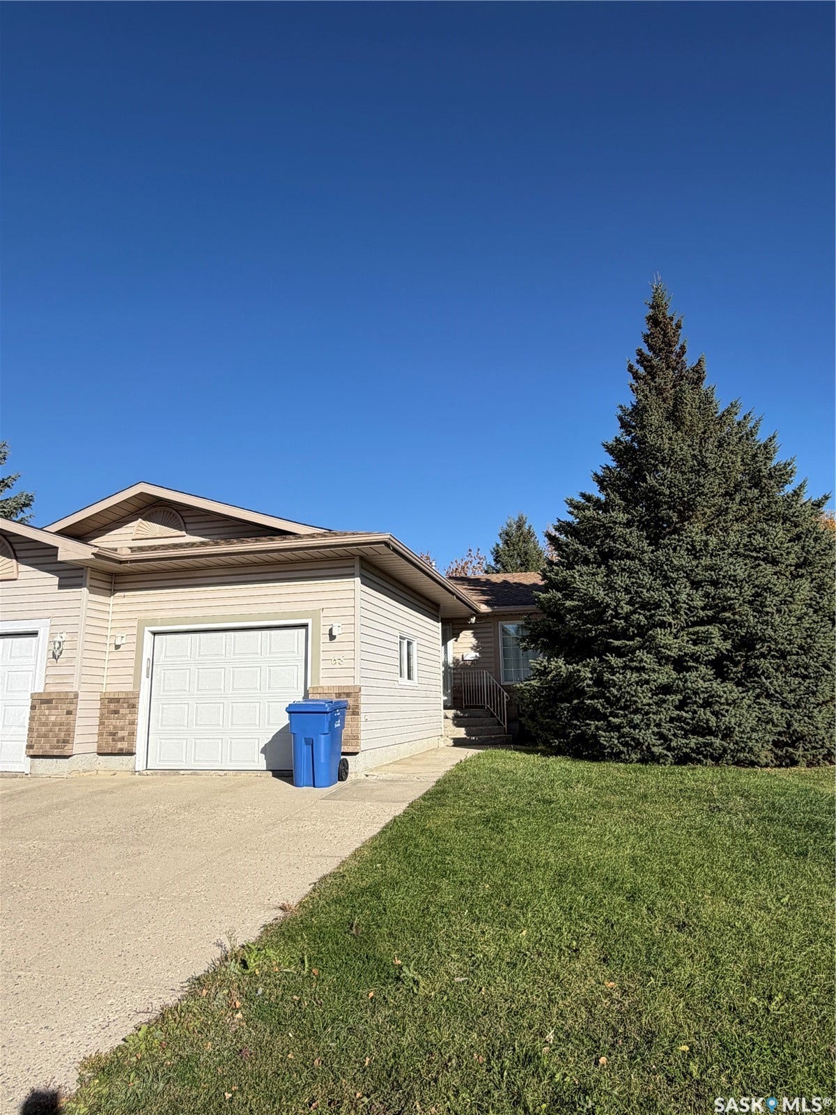 Modern residential home featuring a two-car attached garage with white panel doors, stone and vinyl exterior finishes, and a sloped roofline with contemporary architectural details