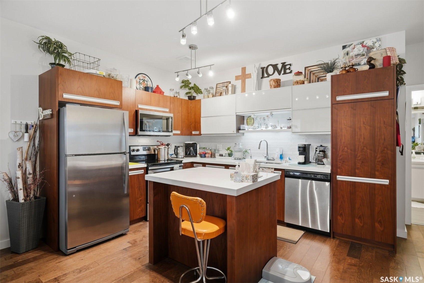 Kitchen featuring wood-finish flooring, stainless steel appliances, white subway tile backsplash, and a central island with a solid surface countertop
