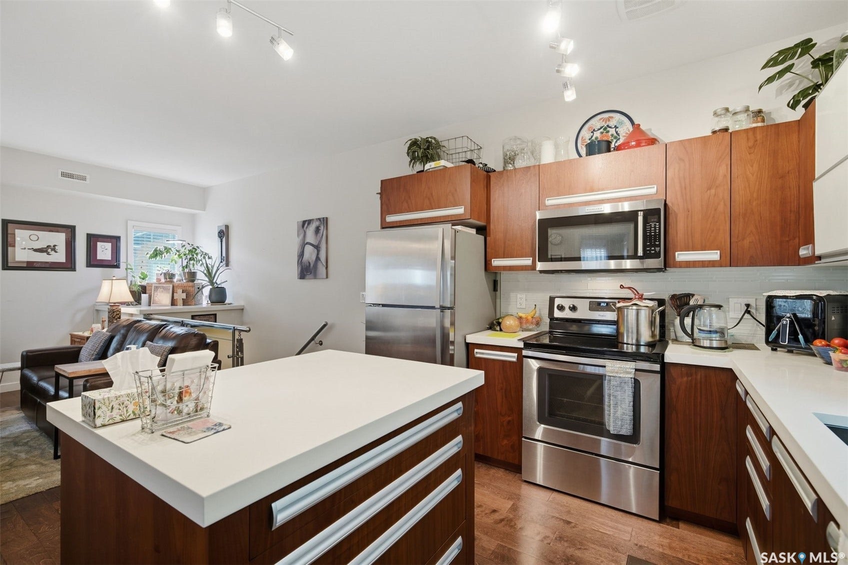 Kitchen featuring an island with a white countertop, wood-finish cabinetry, stainless steel appliances, and a tile backsplash