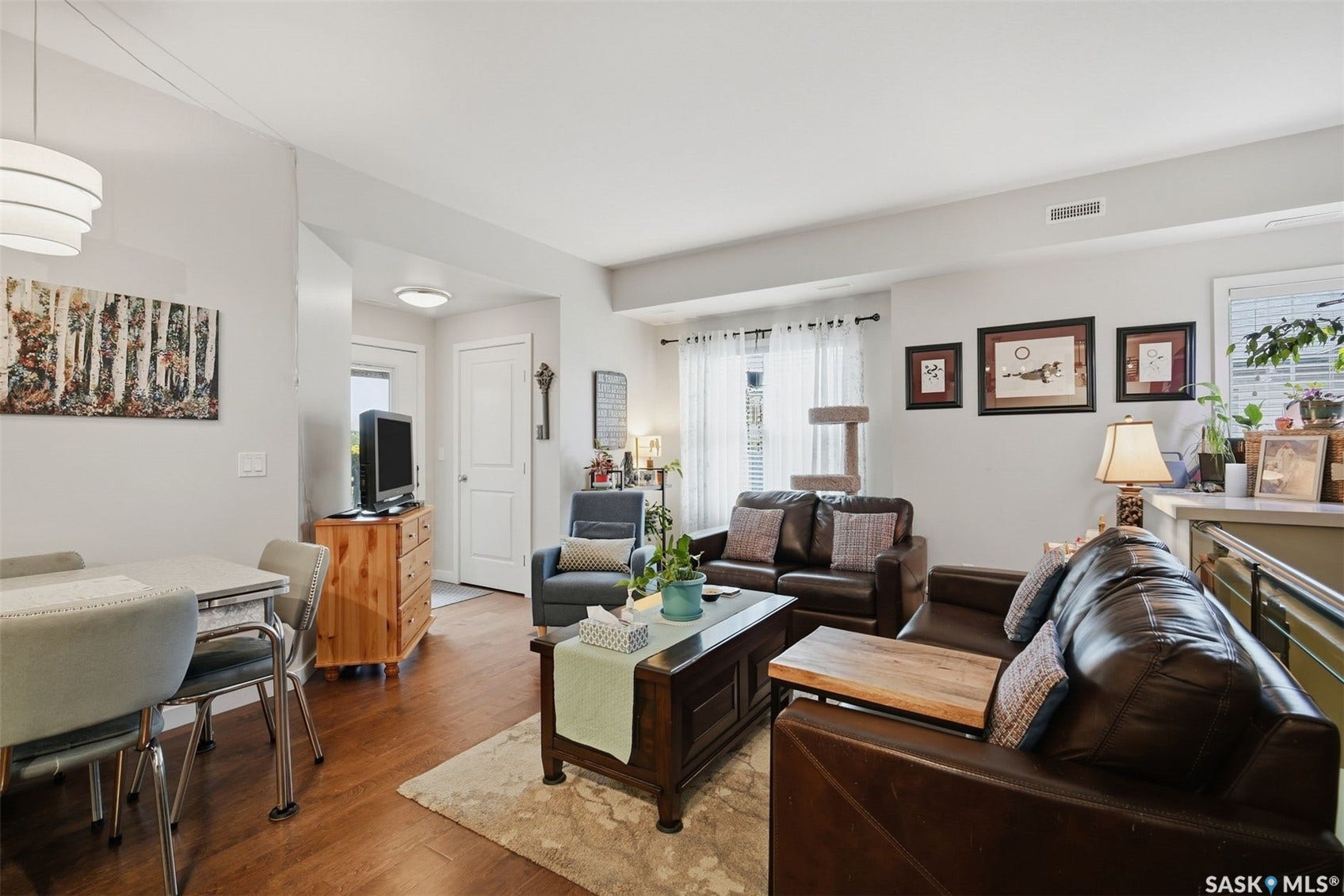 Recessed and pendant lighting illuminate the space, featuring wood-finish flooring and a white paneled door