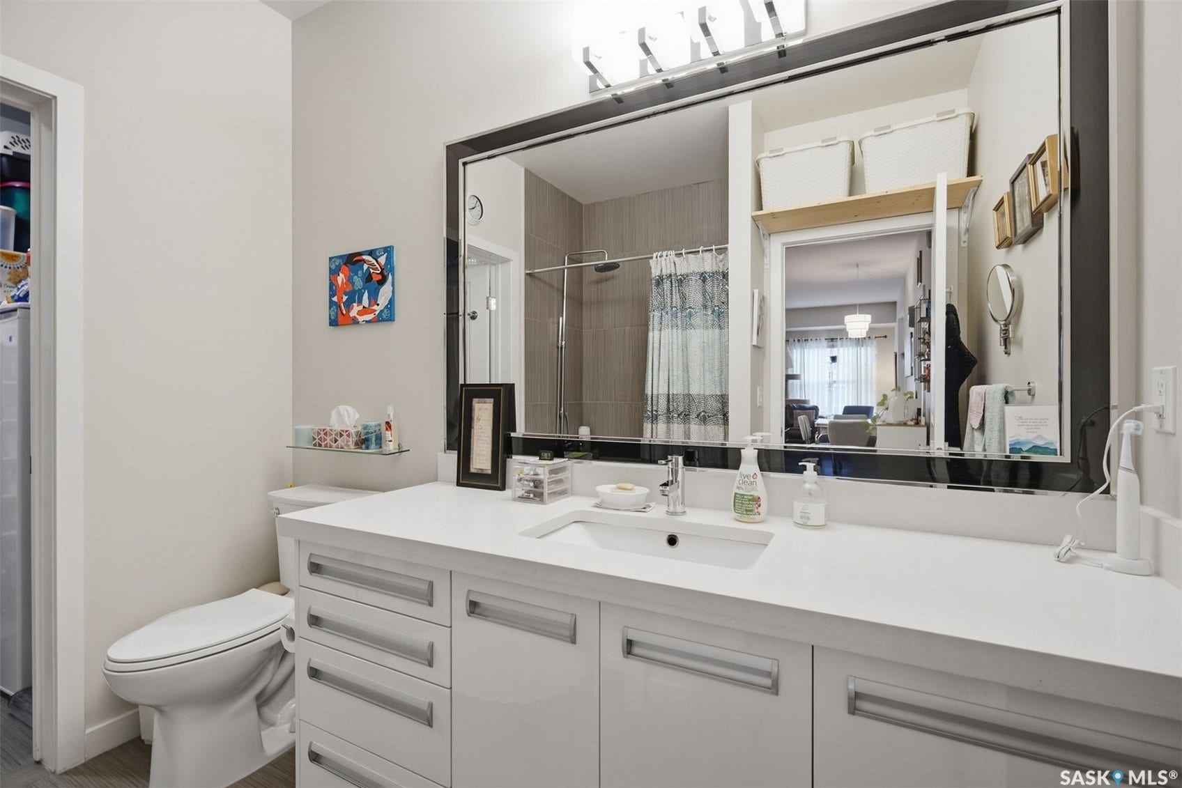 White vanity with multiple drawers, an integrated sink, and a large framed mirror