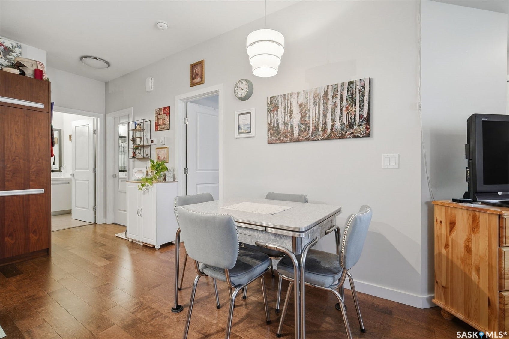 Wood-finish flooring throughout, white interior doors, and a contemporary tiered pendant light fixture