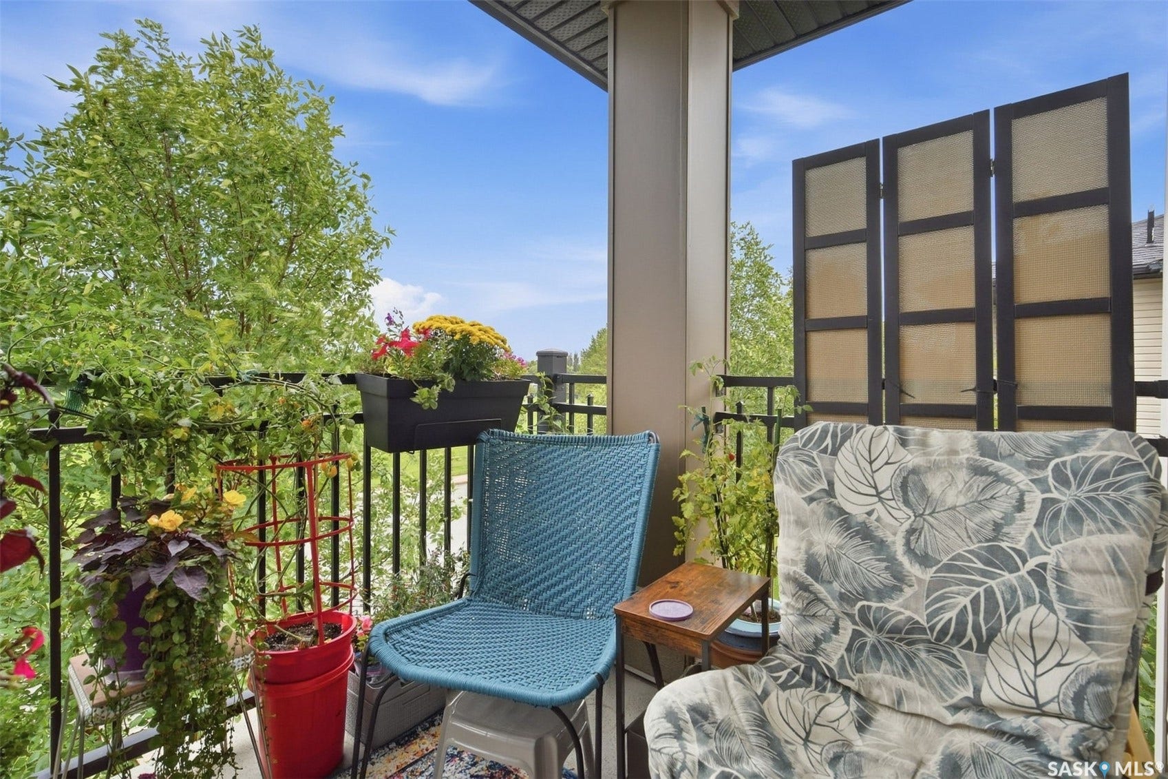 Outdoor balcony featuring an open-air design, black metal railings, and a privacy screen