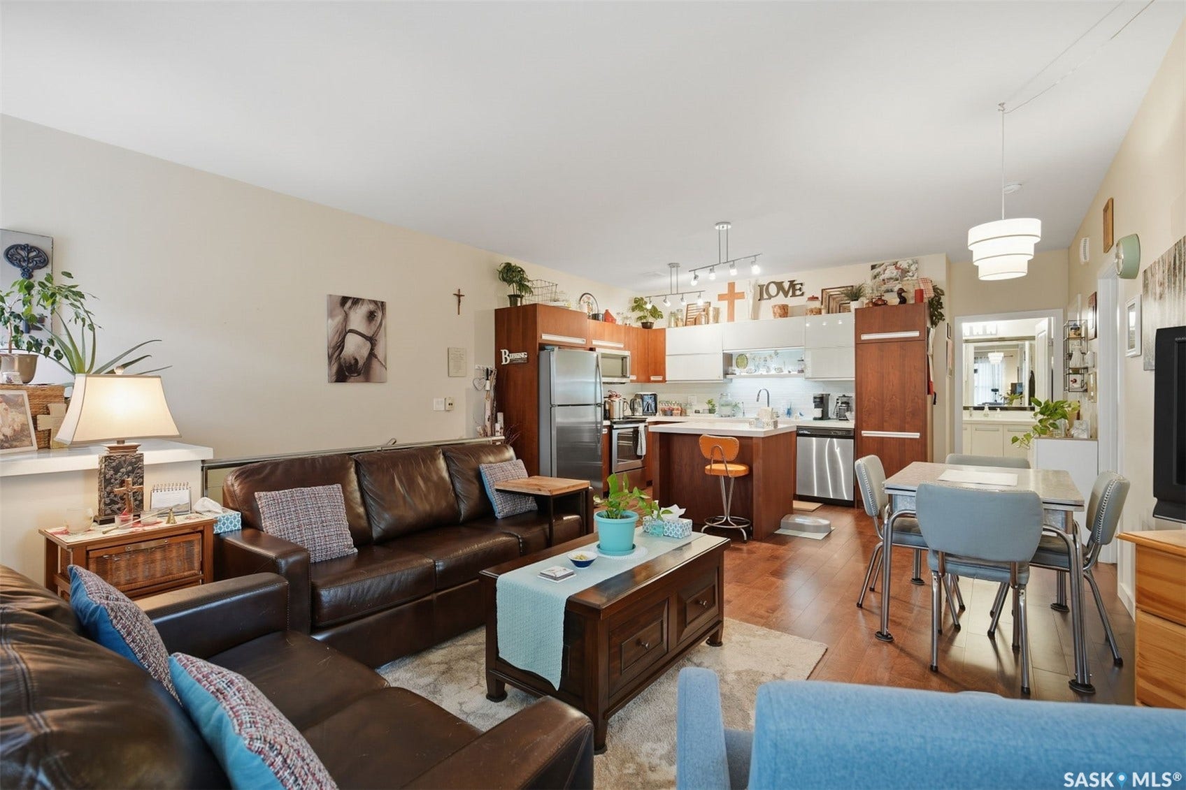 Open concept living space featuring wood-finish flooring, a kitchen island with seating, stainless steel appliances, and built-in cabinetry
