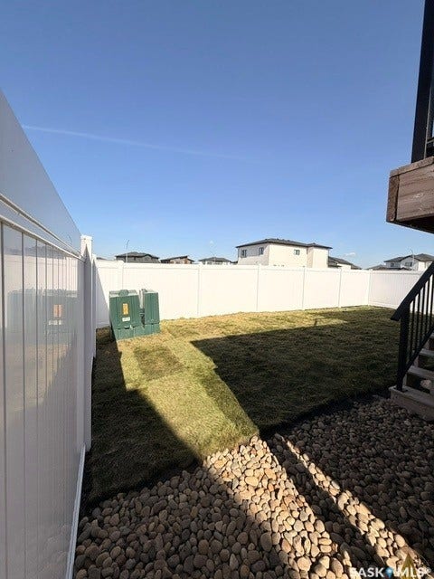 Defined outdoor space featuring a white privacy fence, newly laid sod, and a decorative pebble border