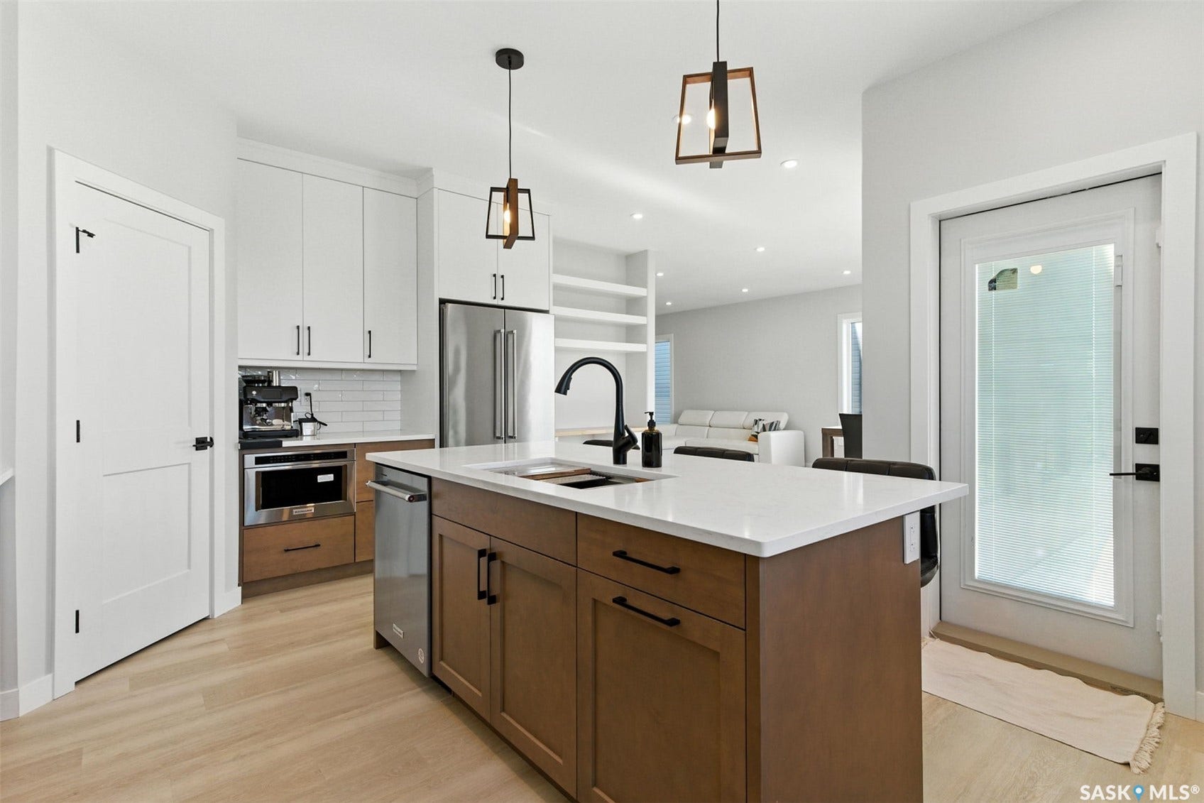 Kitchen featuring a central island with countertop seating, stainless steel appliances, wood-finish flooring, and pendant lighting