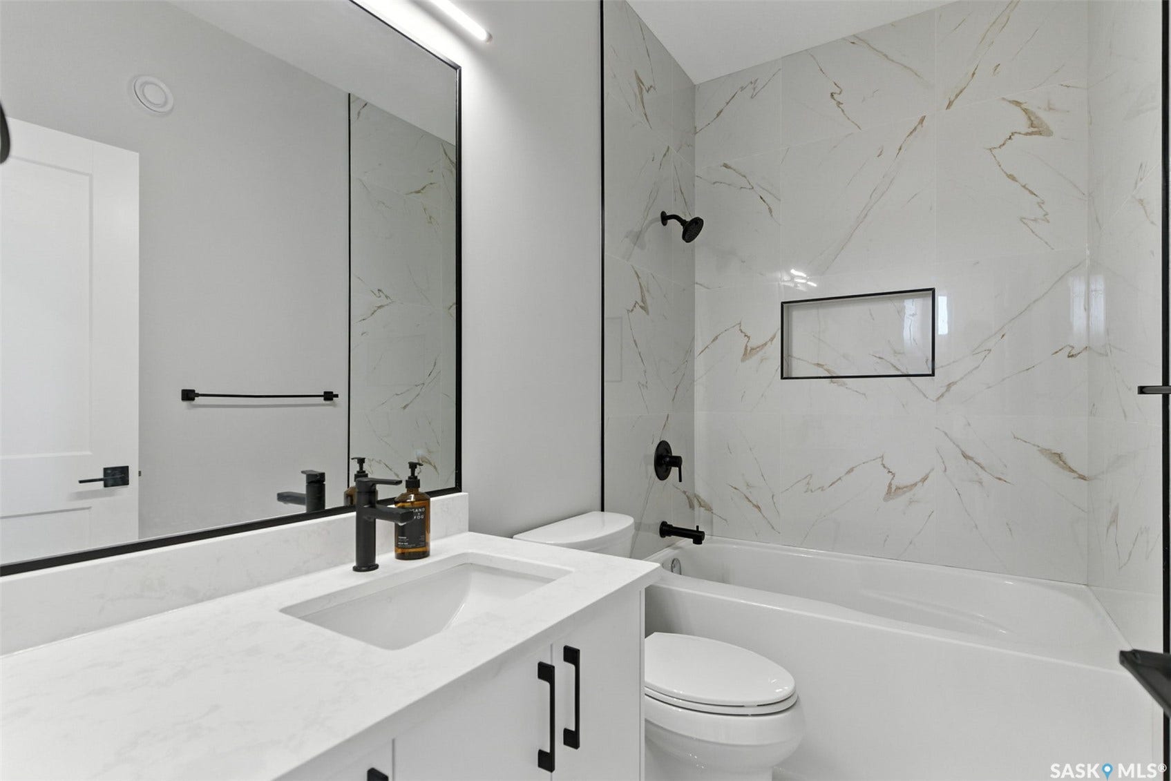 Integrated vanity with a rectangular sink, white countertop, and matte black faucet