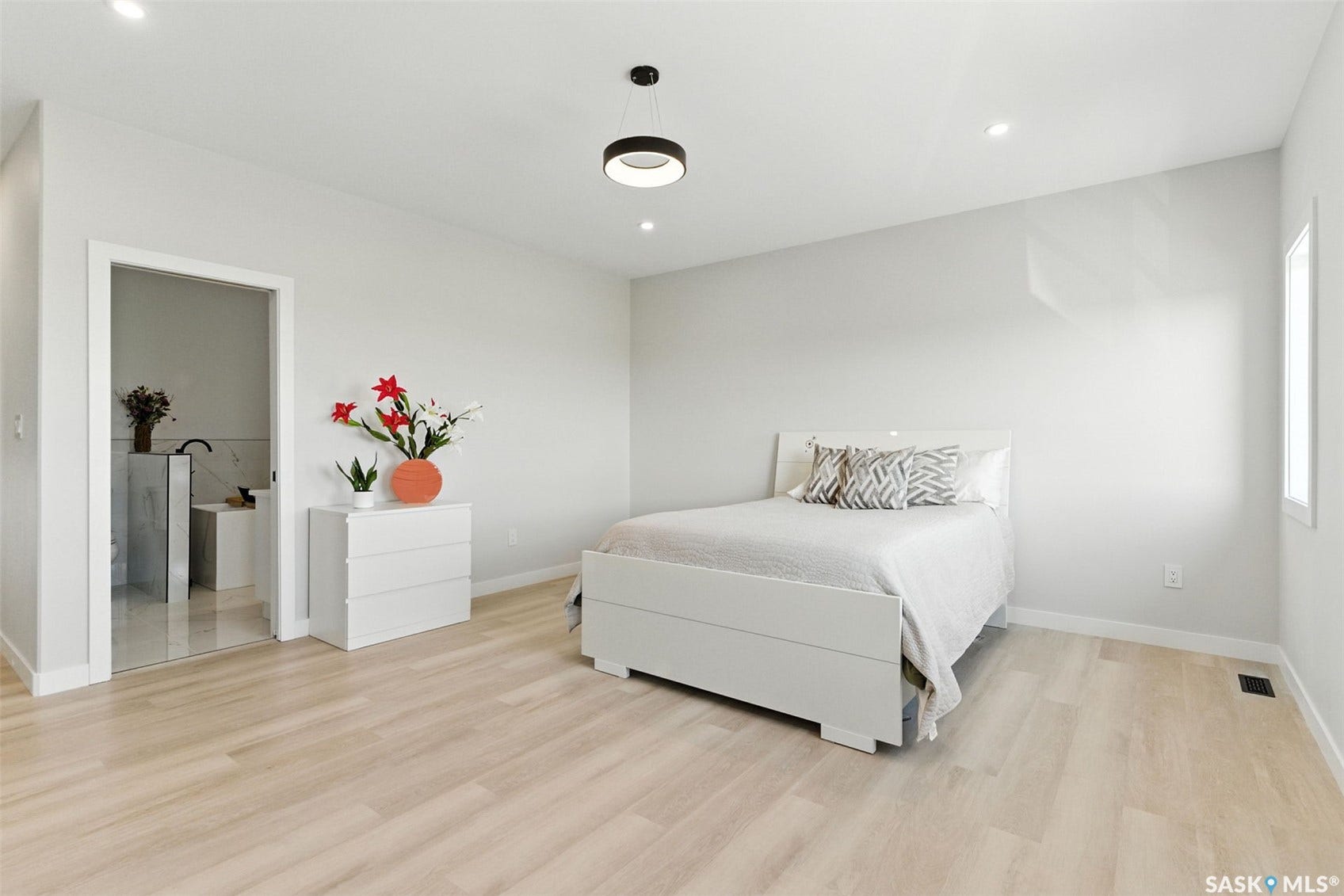 Light wood-finish flooring, recessed lighting, contemporary pendant light fixture, and a window