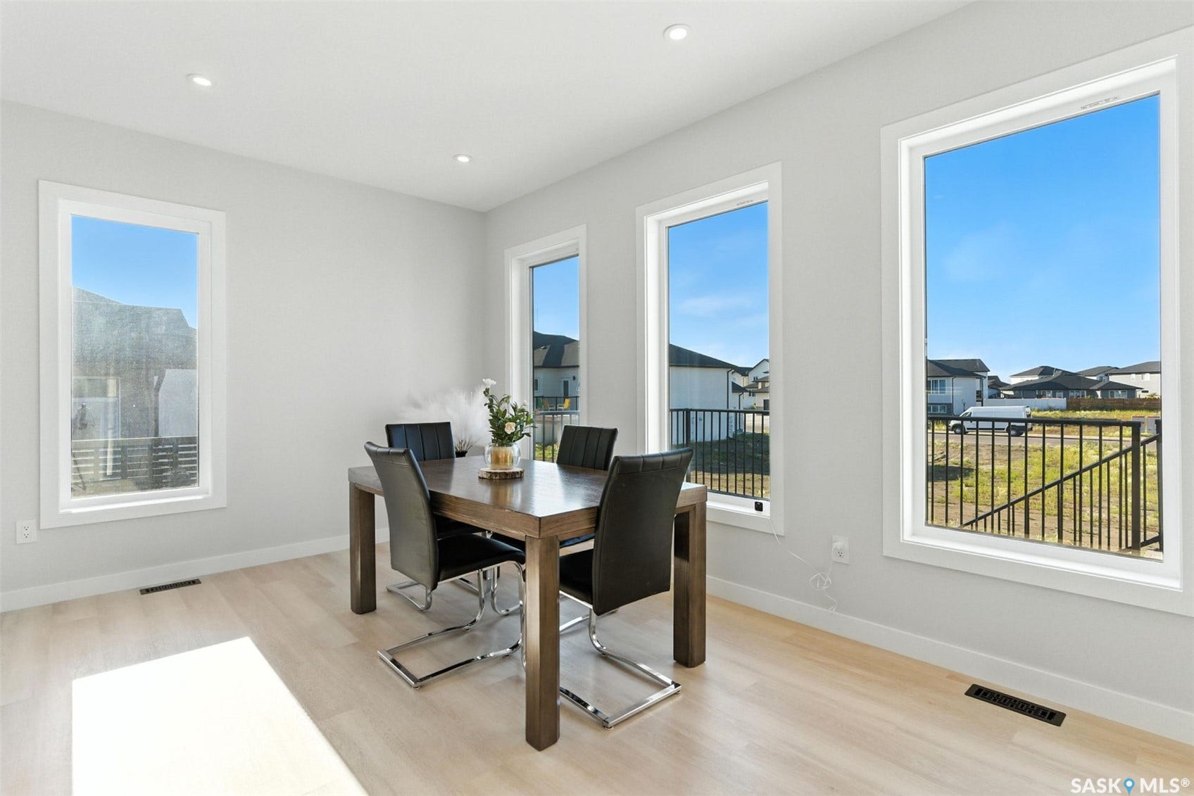 Recessed ceiling lighting, light wood-finish flooring, multiple large windows, and clean white trim