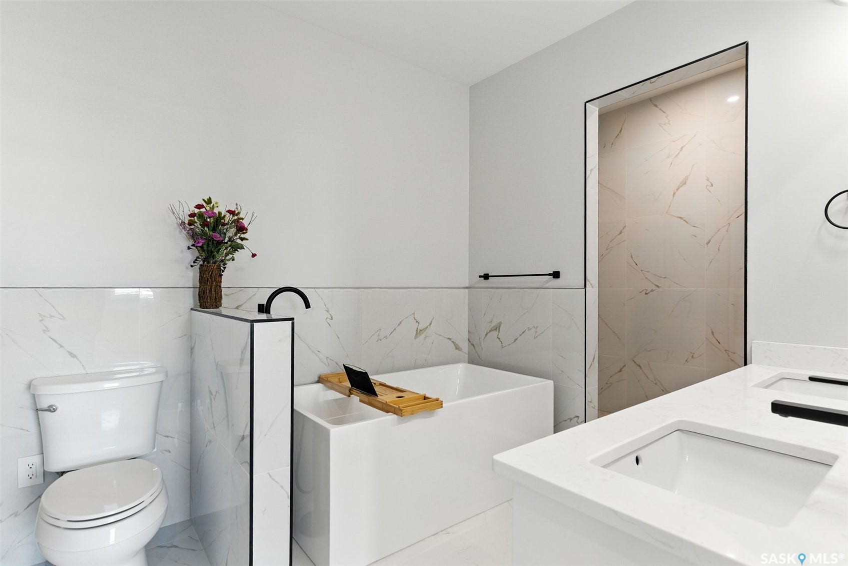 Freestanding soaking tub with a floor-mounted matte black faucet, dual vanity with undermount sinks, and a walk-in shower with full-height tile