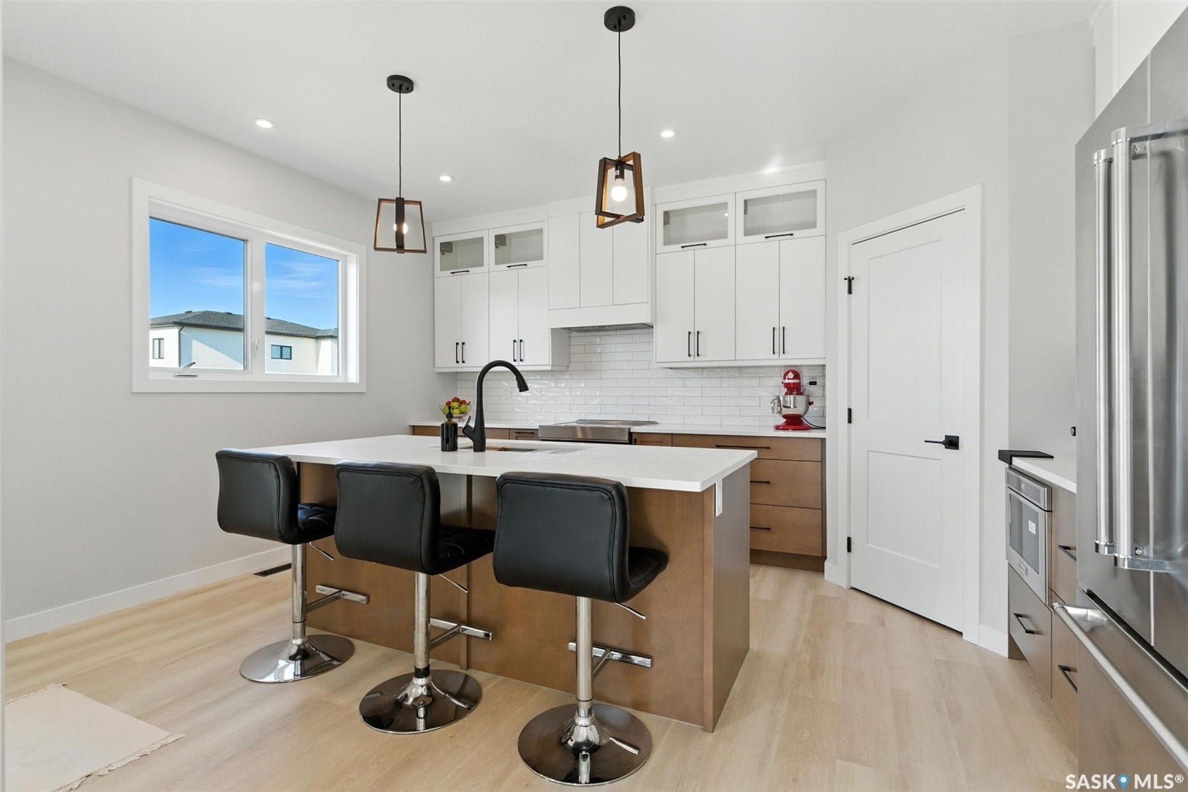 Kitchen featuring a central island with countertop seating, light wood-finish flooring, white upper cabinetry, and stainless steel appliances