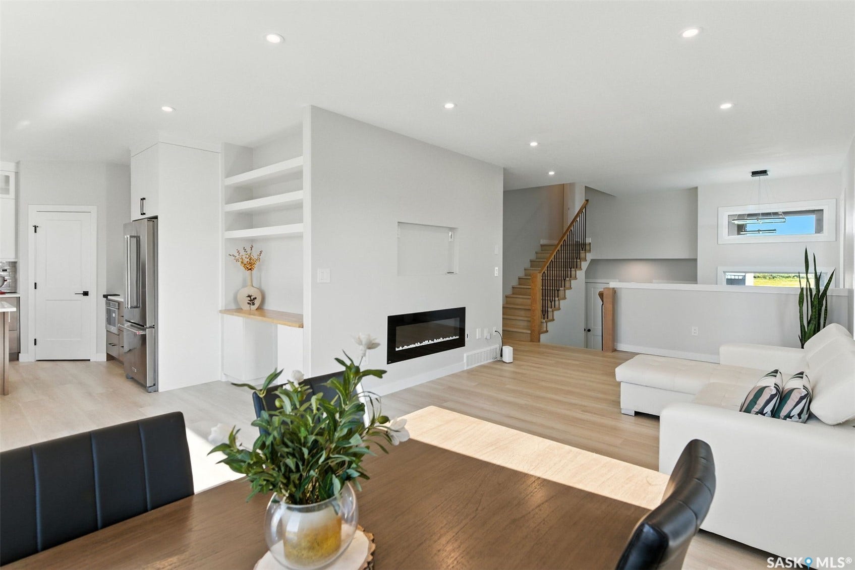 Open-concept living space featuring wood-finish flooring, recessed lighting, and a built-in fireplace