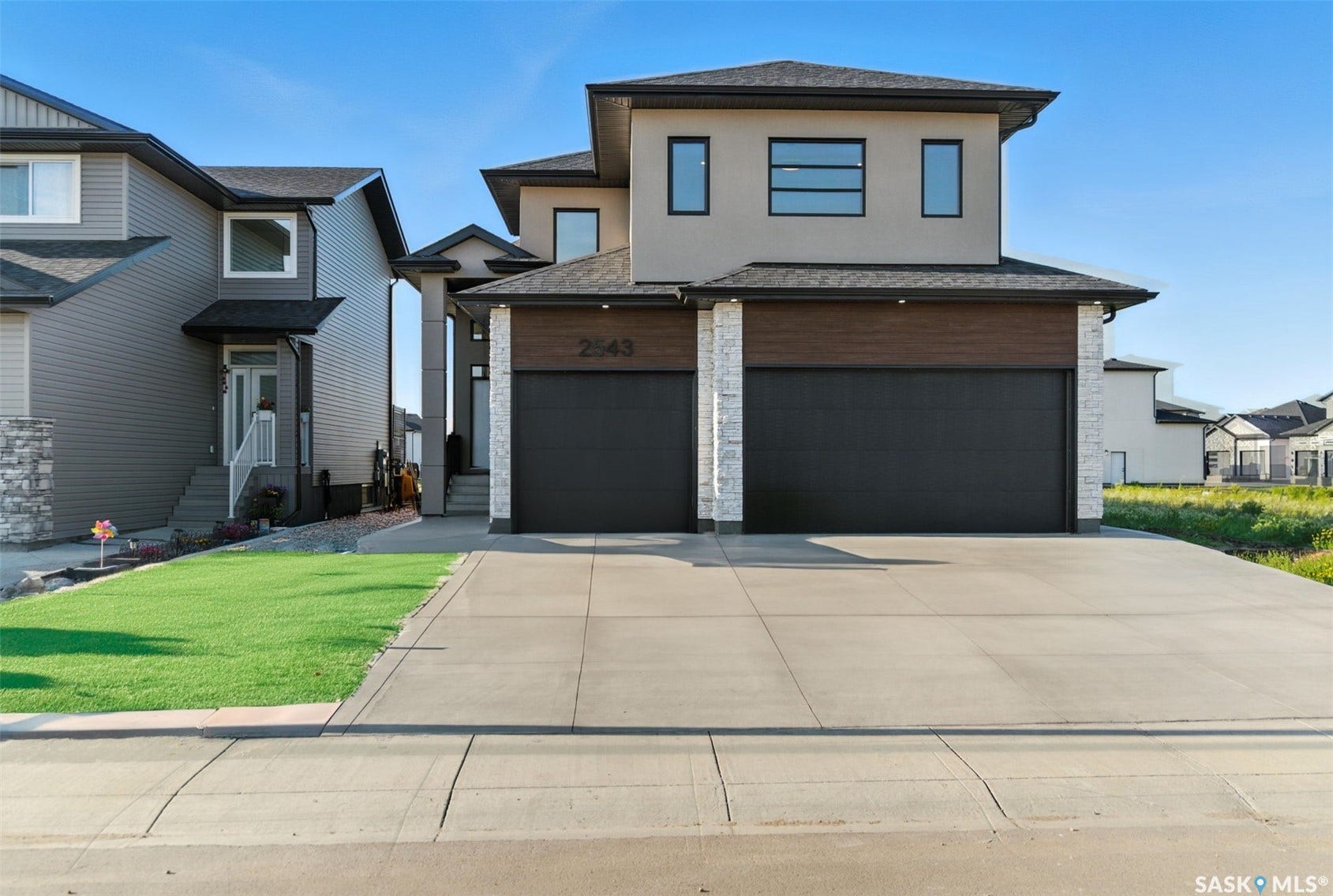 Contemporary exterior with stucco and wood-finish siding, double garage, concrete driveway, and stone accents