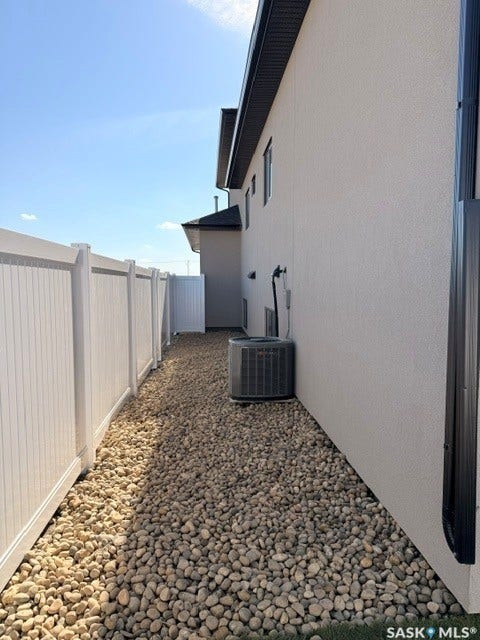 River rock landscaping with a privacy fence, stucco exterior, and black gutters