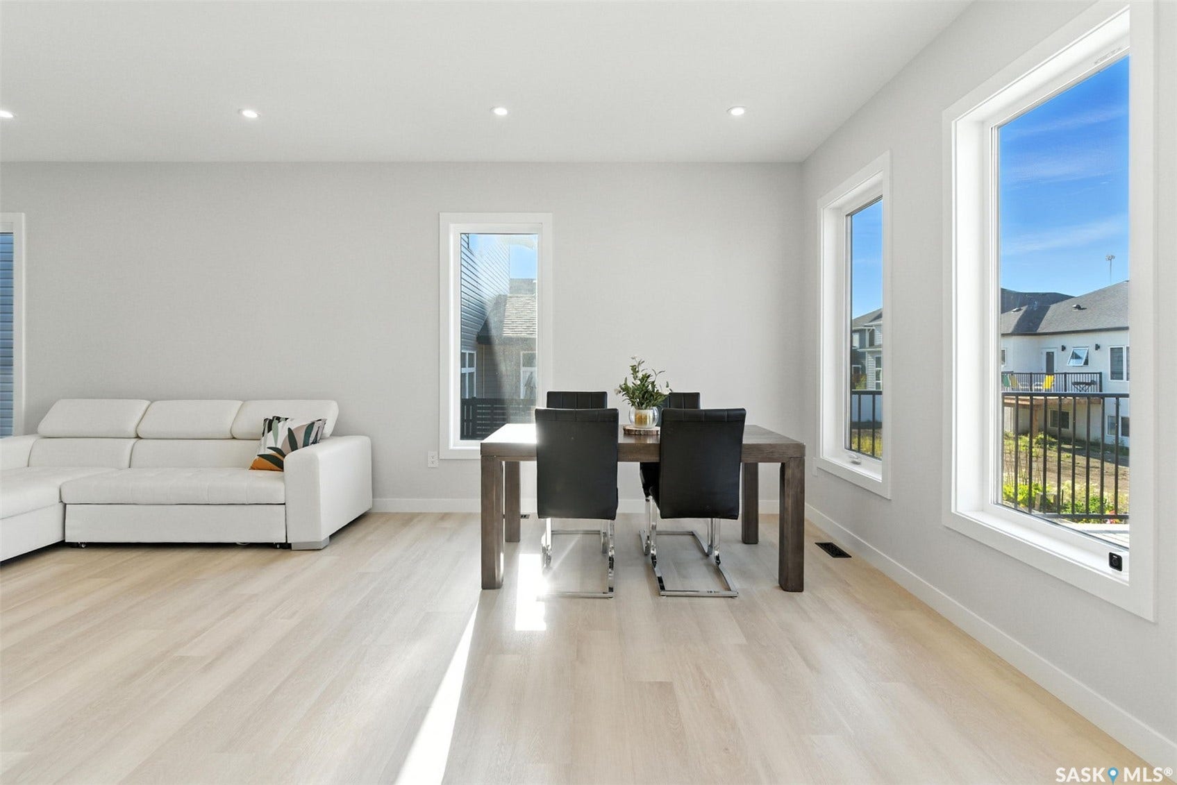 Recessed lighting, light-toned wood-finish flooring, multiple large windows, and a neutral wall palette