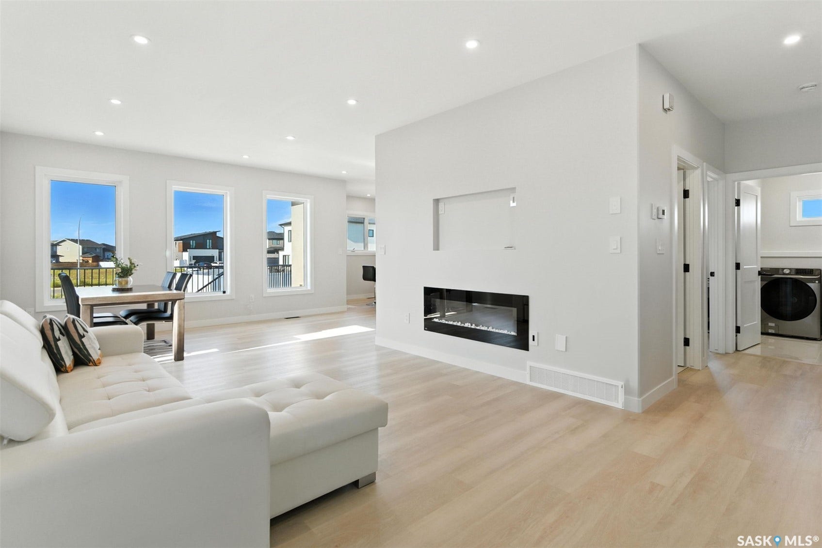 Recessed lighting throughout, light wood-finish flooring, and a built-in linear electric fireplace