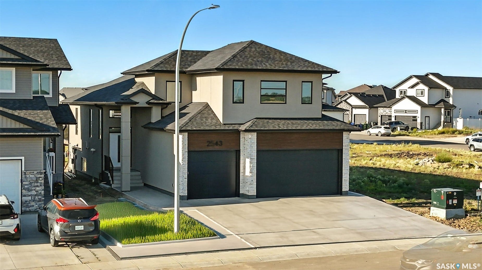 Contemporary exterior with a dark shingle roof, stucco and stone-finish siding, and integrated double garage with dark doors