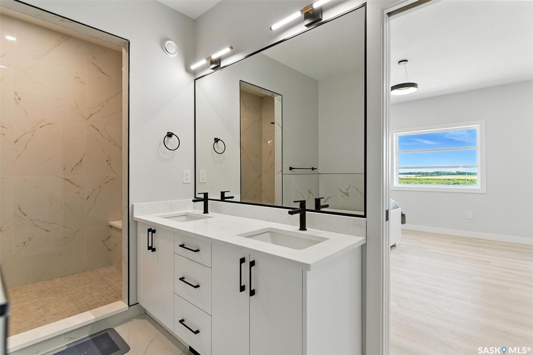 Dual vanity with white cabinetry, matte black hardware, and an oversized mirror