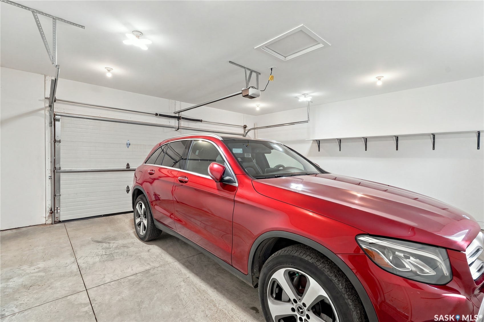 Attached garage featuring an automatic overhead door, concrete flooring, recessed lighting, and wall-mounted shelving