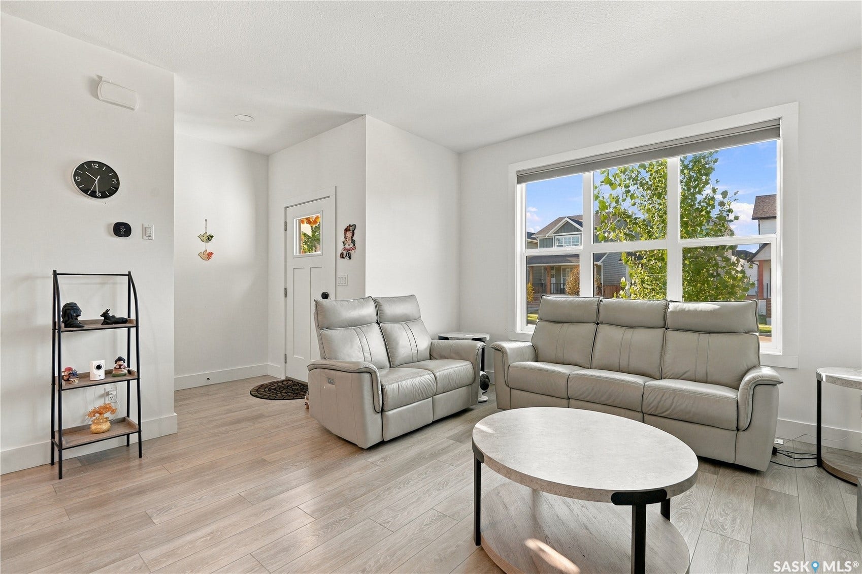 Bright living space featuring wood-finish flooring, a large multi-pane window, and a white entry door with frosted glass