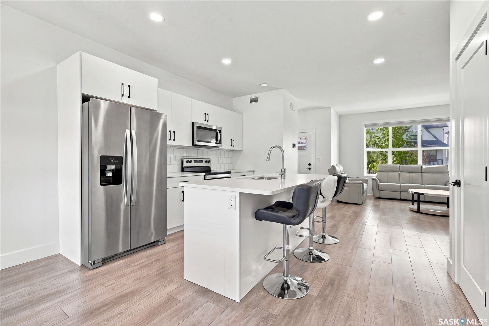 Kitchen featuring white cabinetry, stainless steel appliances, a center island with sink, recessed lighting, and wood-finish flooring