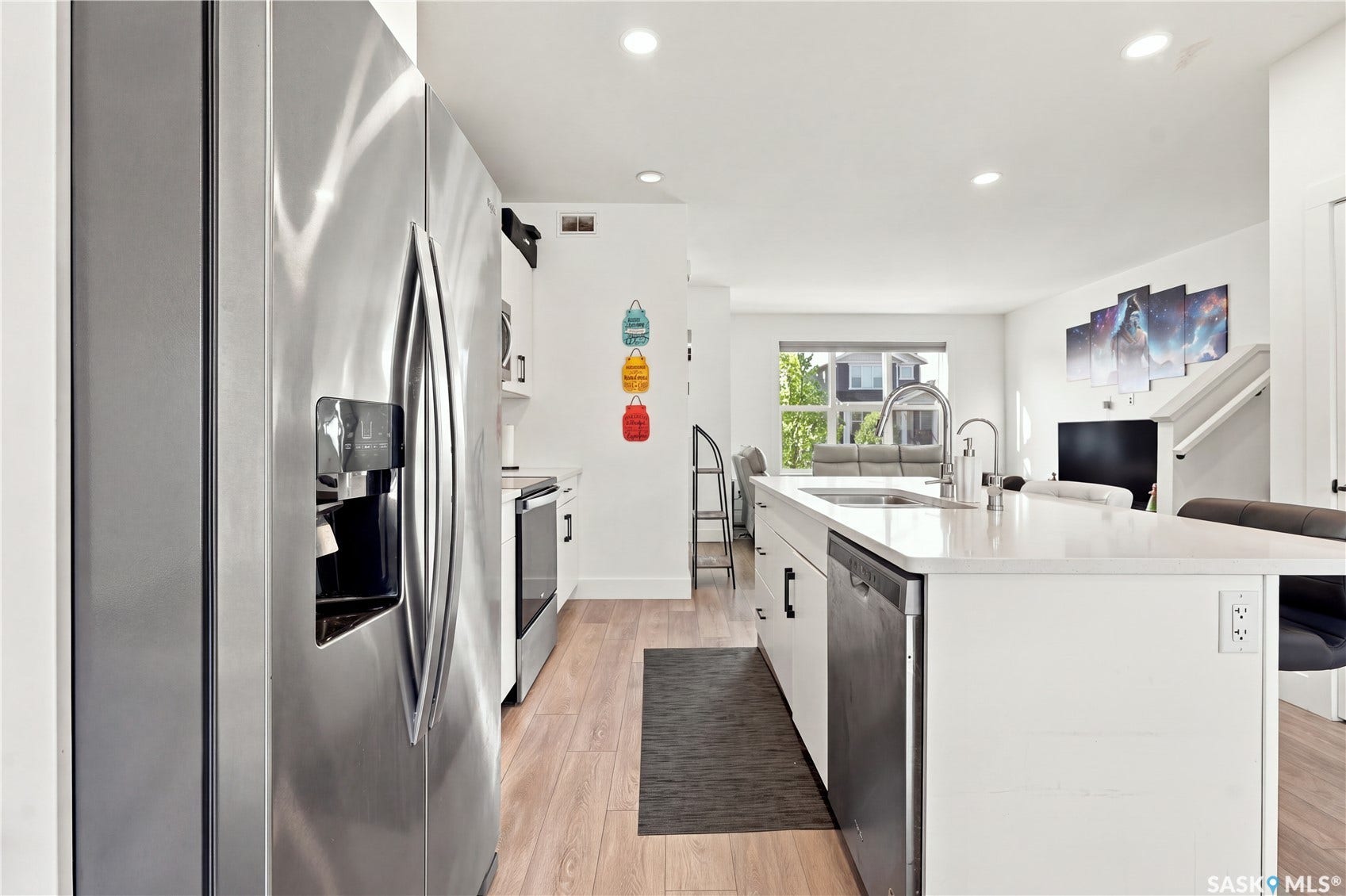 Kitchen featuring an oversized island, stainless steel appliances, recessed lighting, wood-finish flooring, and white cabinetry