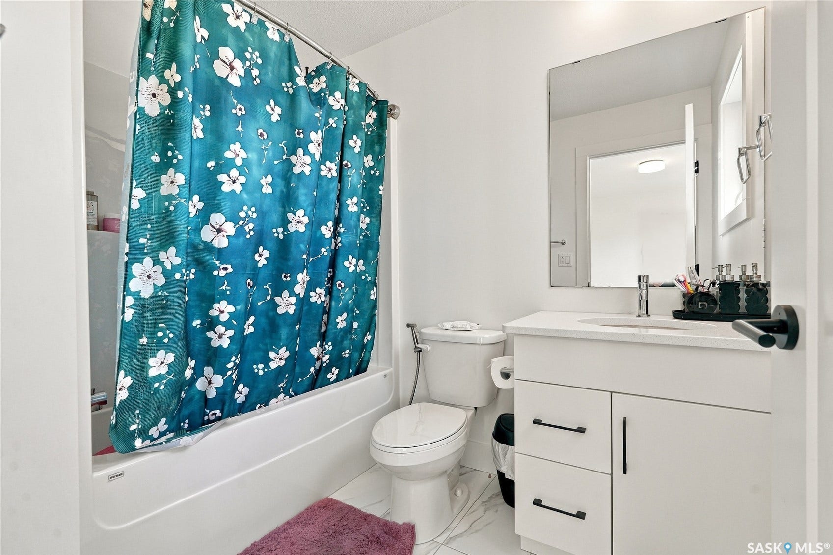 White vanity with a single basin, stainless steel faucet, and black hardware