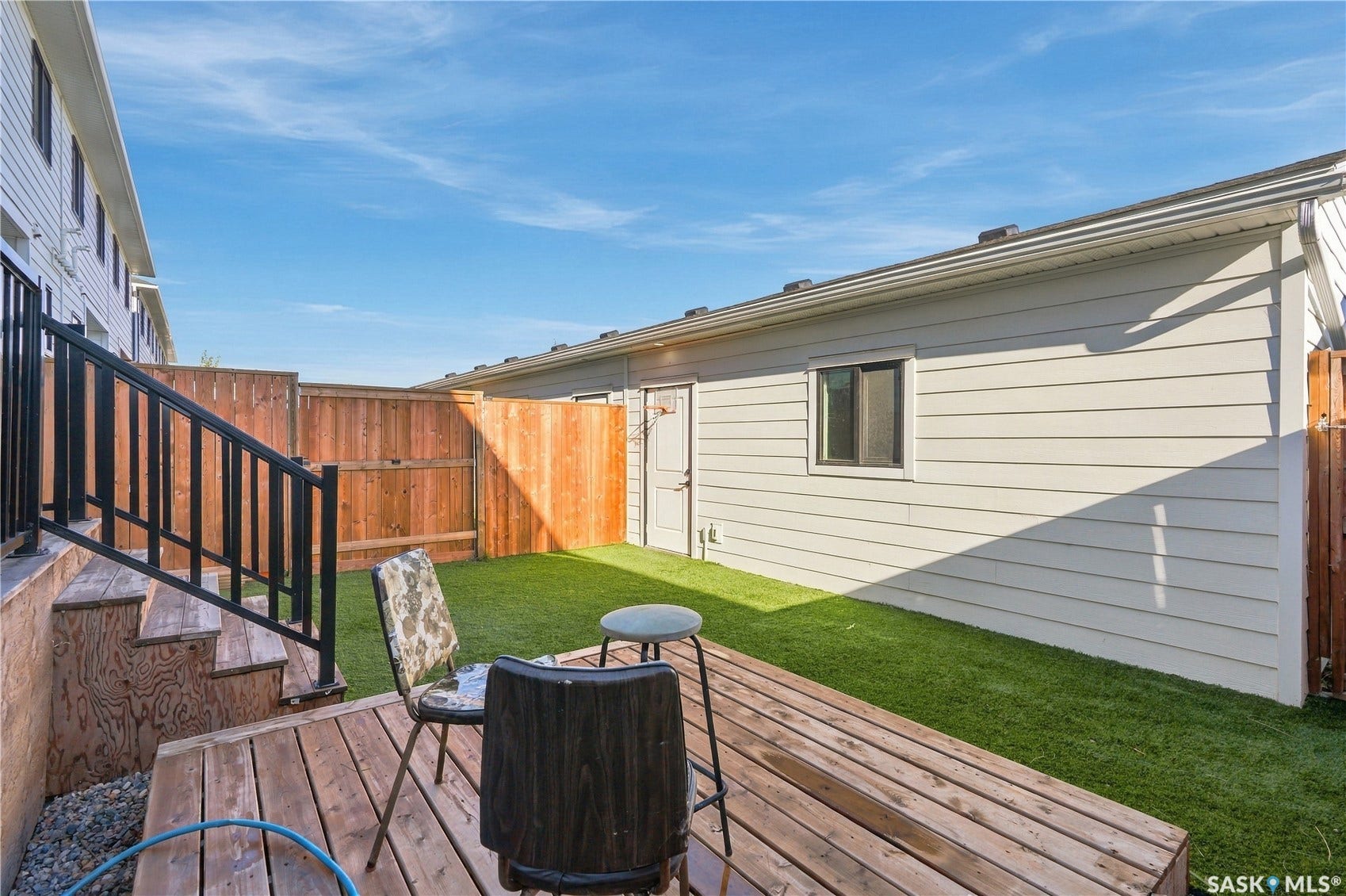 Private backyard featuring a wood deck, artificial turf, and wood privacy fencing