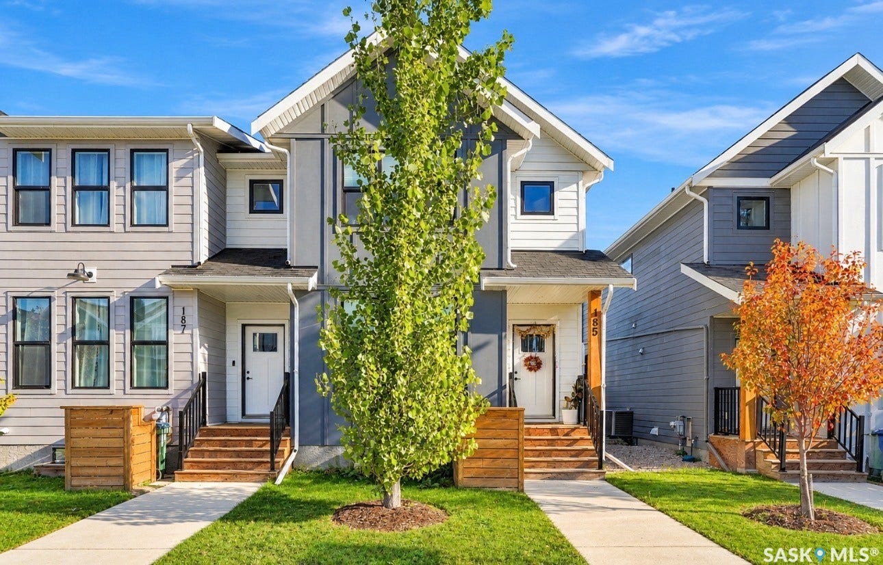 Contemporary exterior with multi-toned siding, black-framed windows, a covered entry, and a concrete walkway