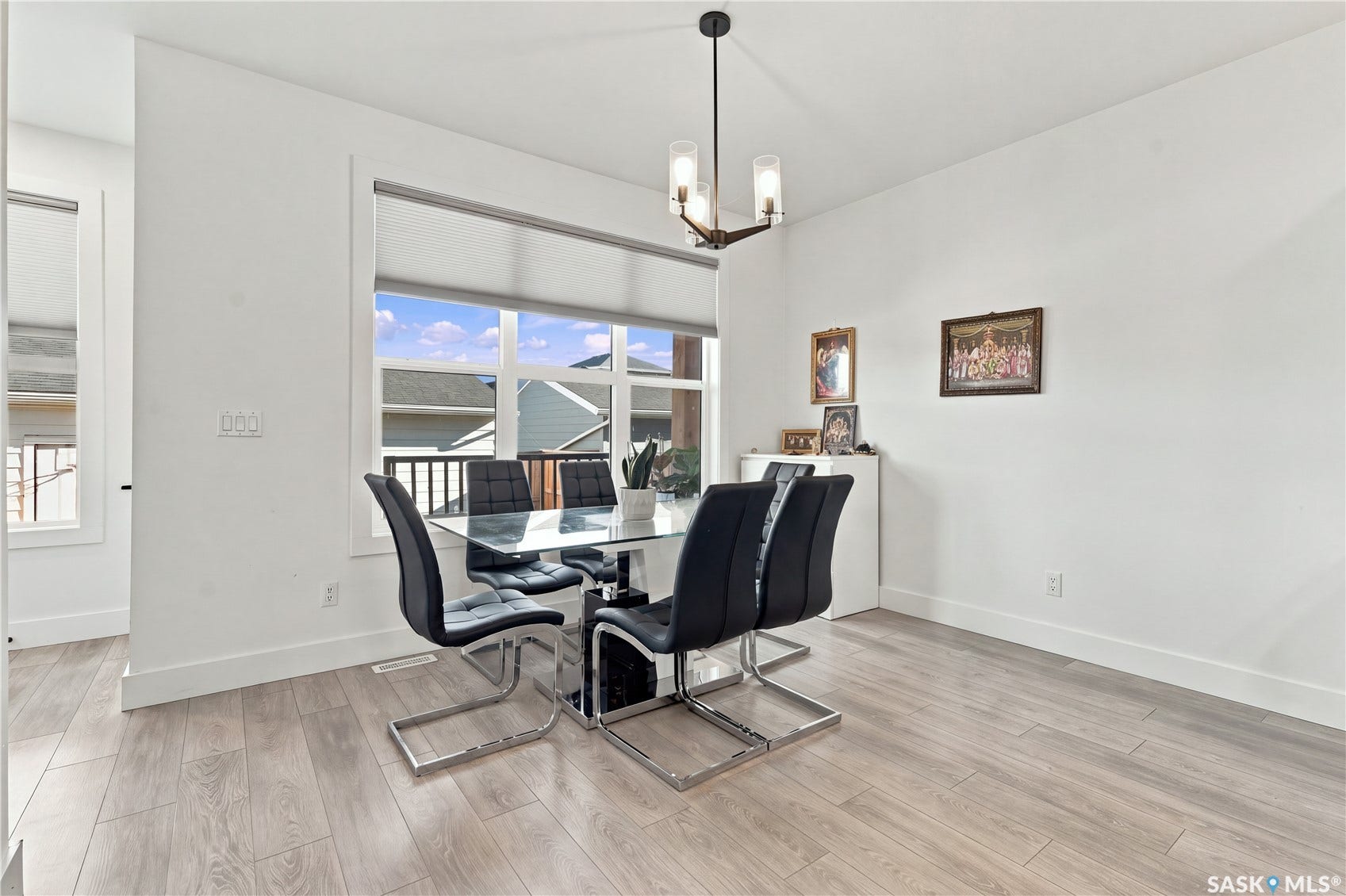 Large window with roller shade, wood-finish flooring, and a contemporary ceiling light fixture