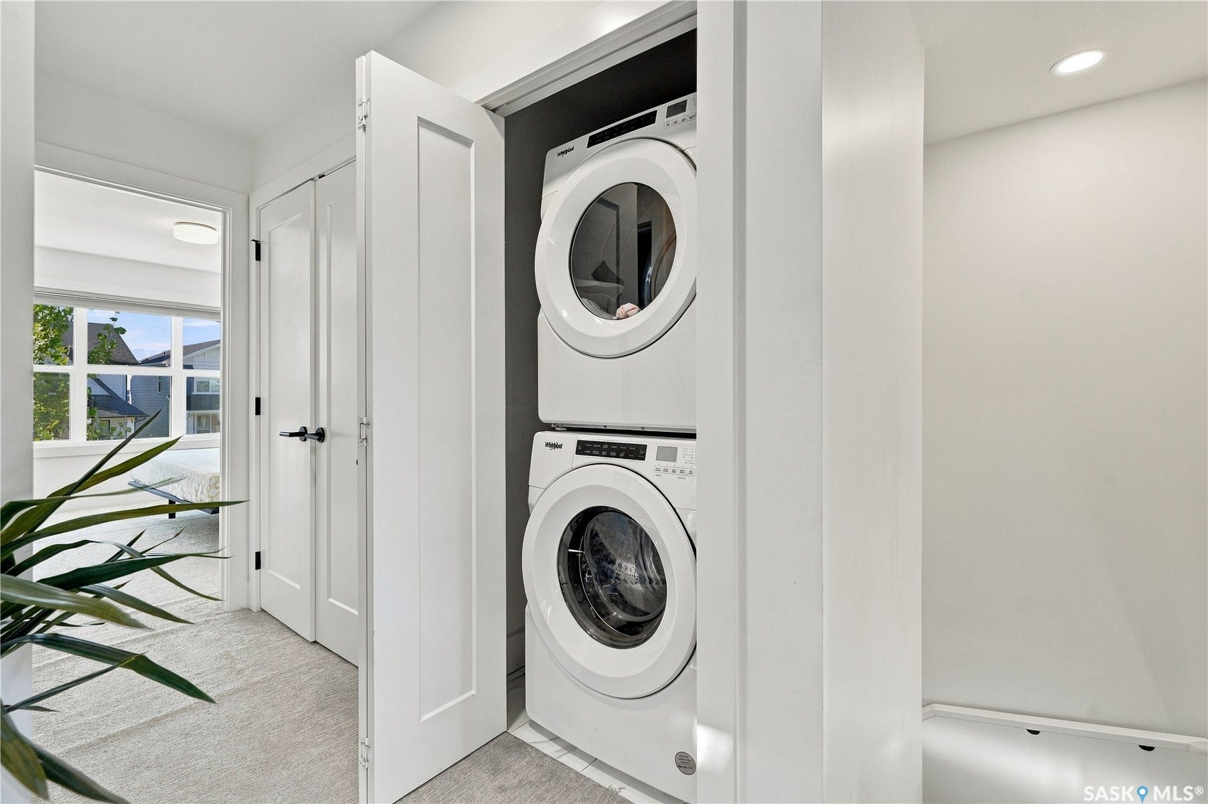 Built-in stacked washer and dryer, recessed ceiling lighting, and white paneled doors