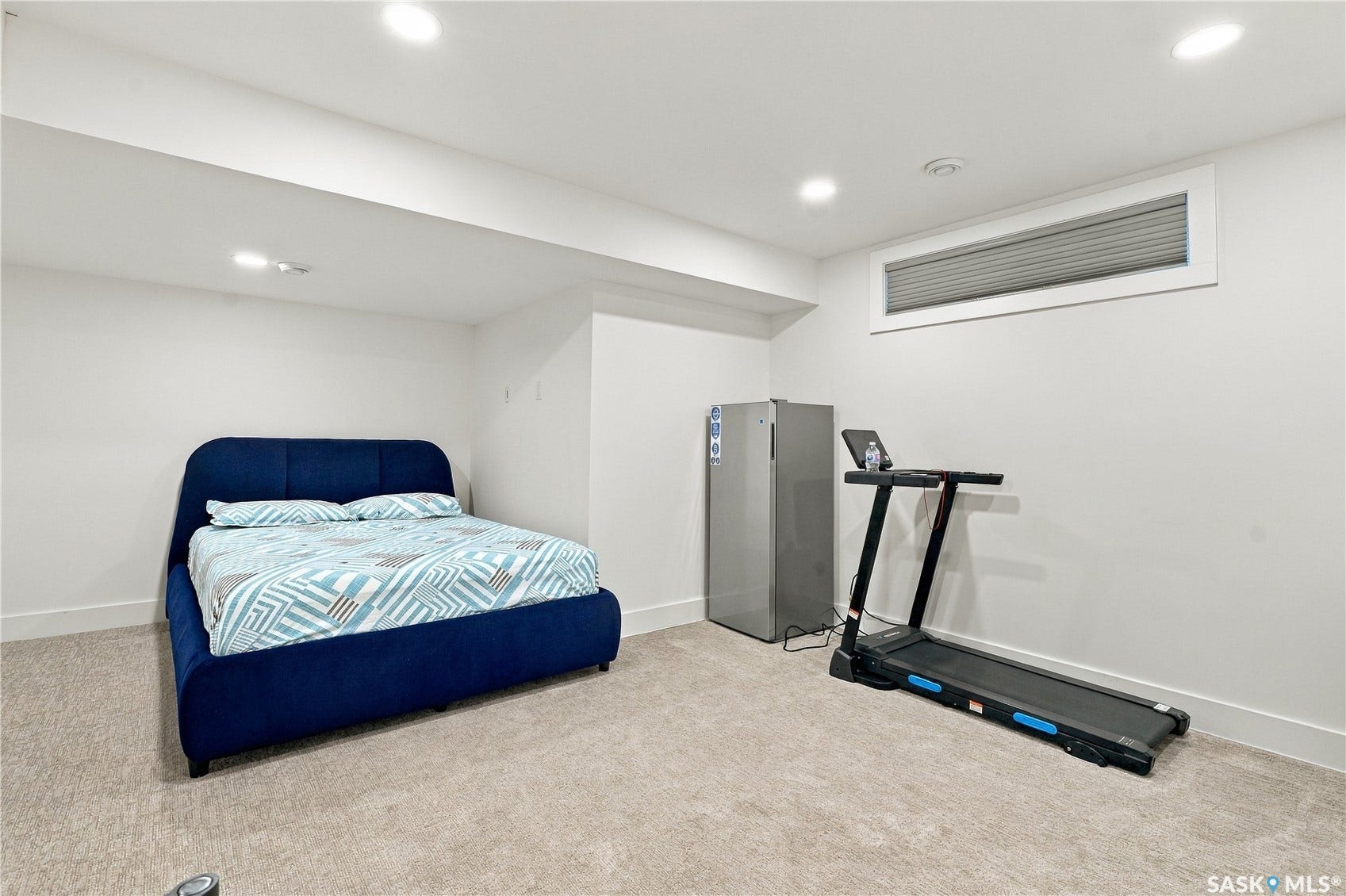 Recessed lighting illuminates the carpeted room with white walls and a horizontal window featuring blinds
