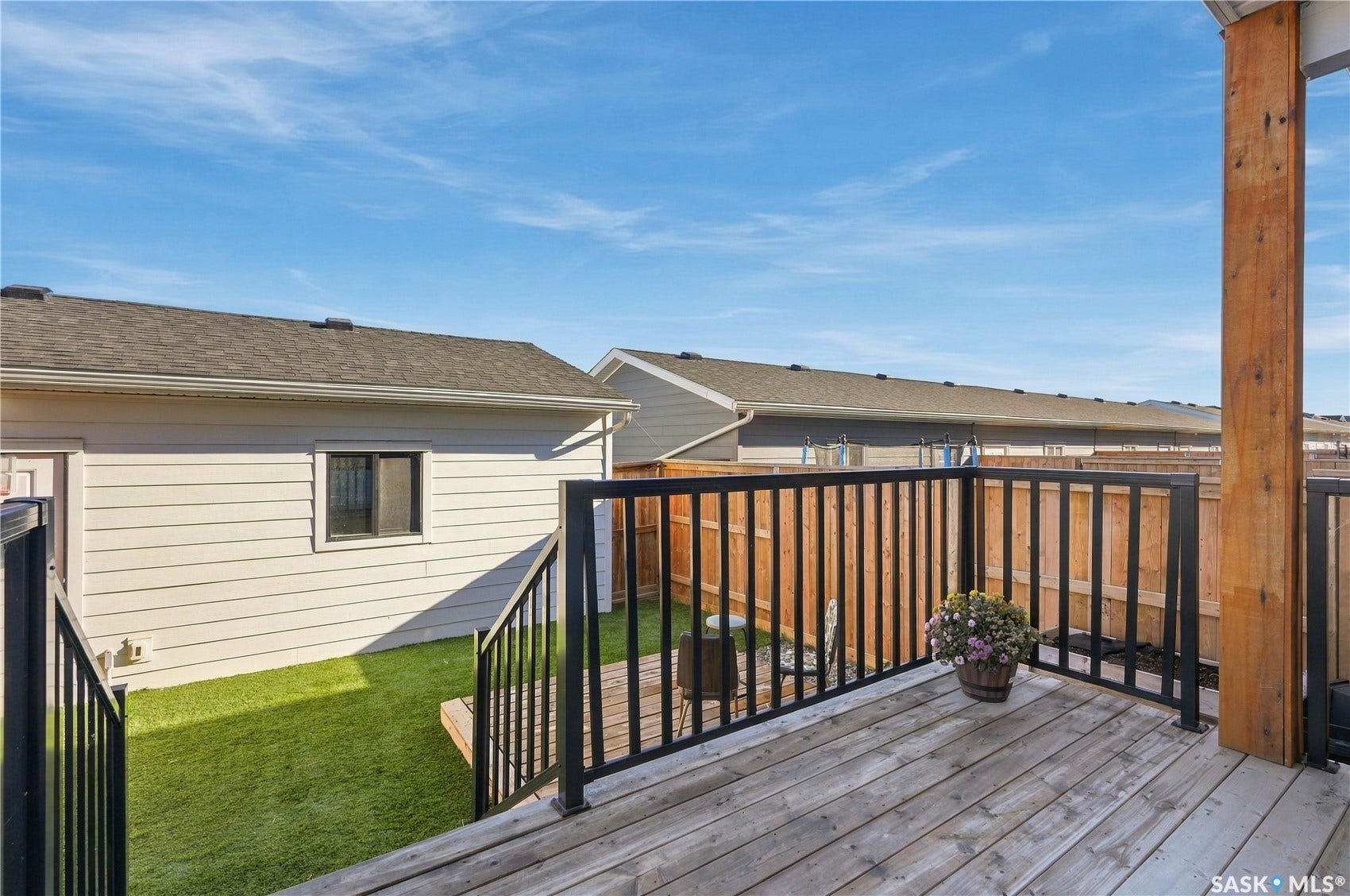 Wood-finish decking with black metal railings, a natural wood post, and a lower-level landing
