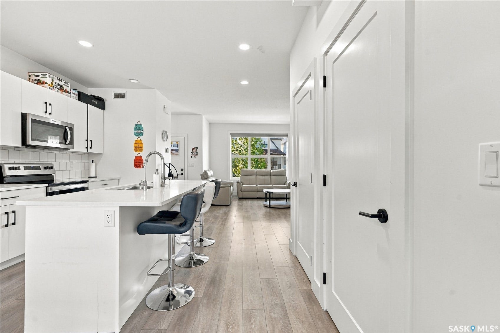Modern kitchen featuring white cabinetry, stainless steel appliances, a center island with bar seating, and wood-finish flooring