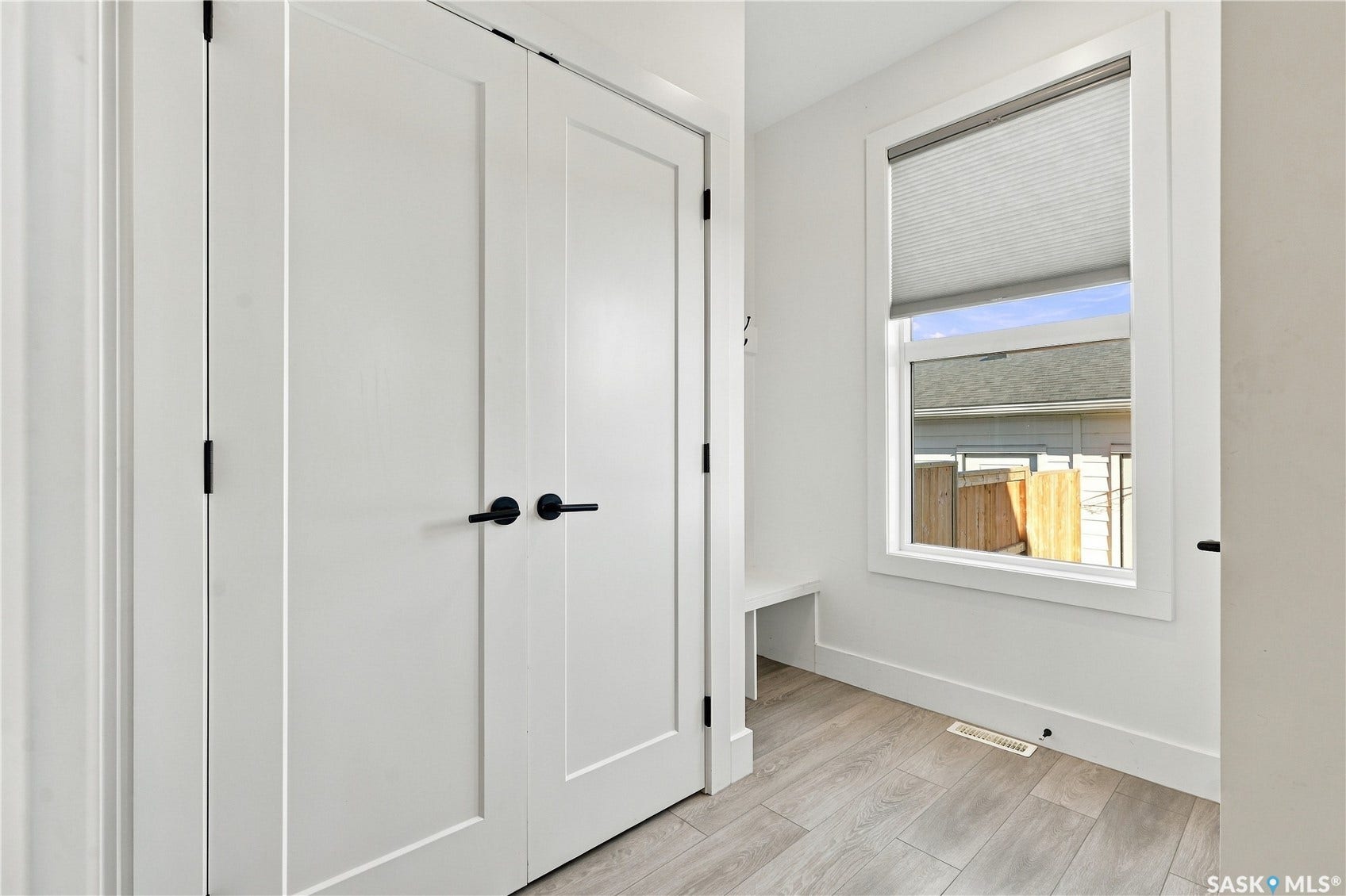 White interior doors with black hardware, wood-finish flooring, and a built-in bench under a window