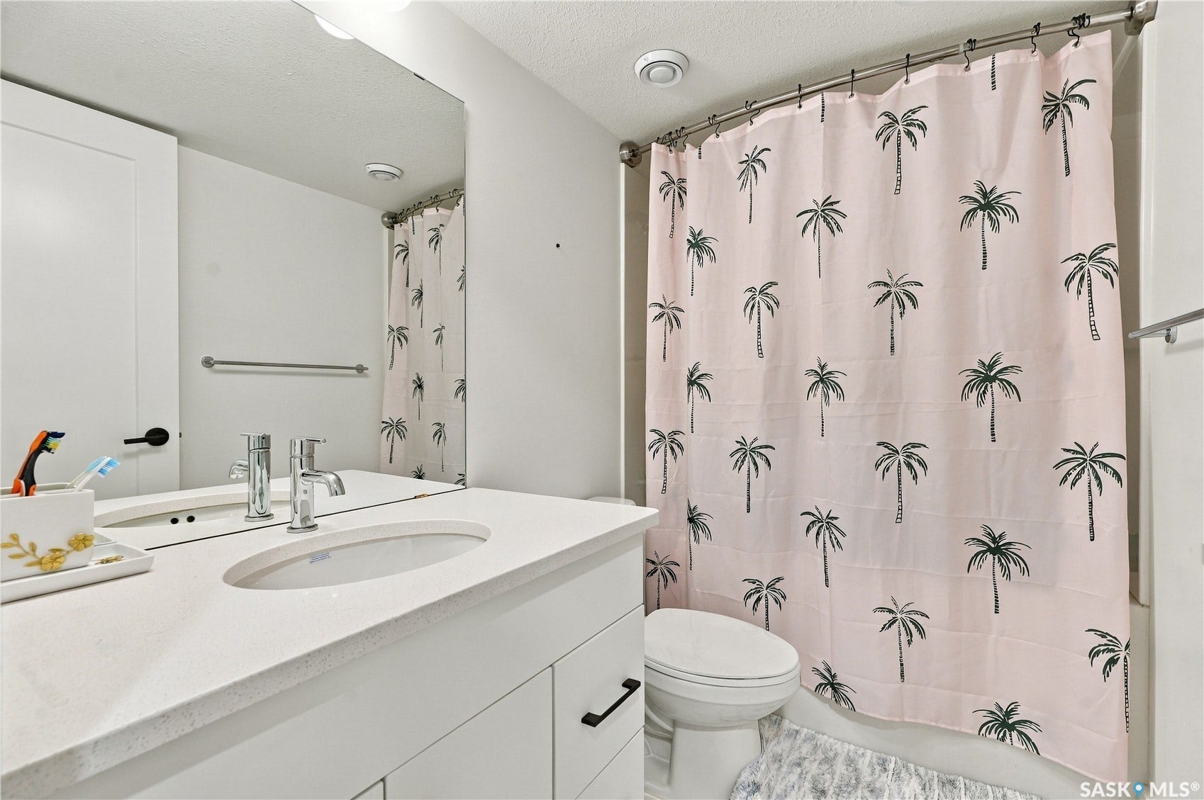 Vanity with integrated sink and chrome faucet, large frameless mirror, and overhead lighting fixture